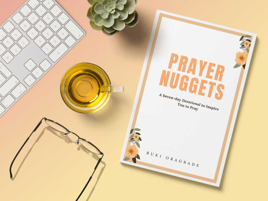 Prayer devotional book laying on desk with keyboard, glasses, tea, and a succulent plant.